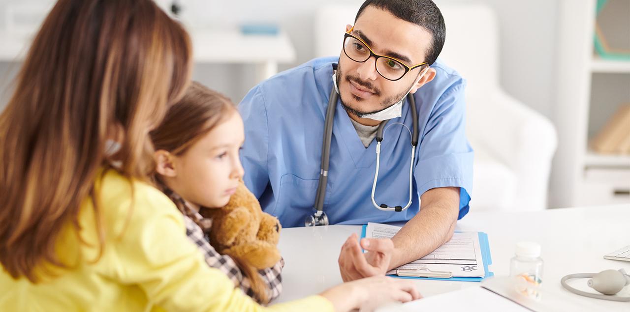 Portrait of a doctor talking to young mother trying to help her and her daughter during consultation.